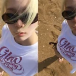 aespa Winter taking a selfie on the beach wearing sunglasses and a white t-shirt