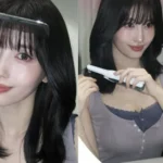 TWICE Momo holding styling tools in front of a mirror in a purple sleeveless top