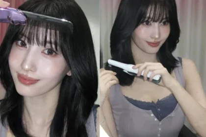 TWICE Momo holding styling tools in front of a mirror in a purple sleeveless top