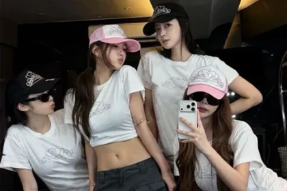T-ara four members wearing pink and black caps posing together in a practice room for their 17th anniversary