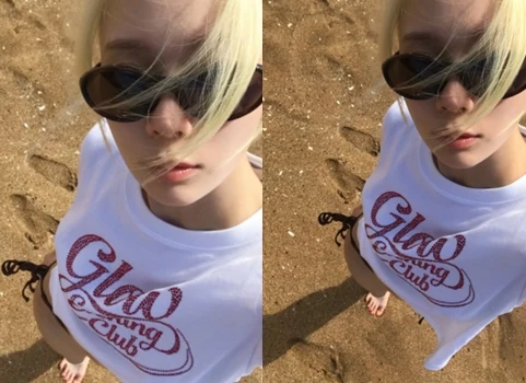 aespa Winter taking a selfie on the beach wearing sunglasses and a white t-shirt