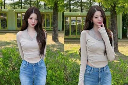 Jang Wonyoung wearing a beige halter-neck top and denim jeans at an amusement park