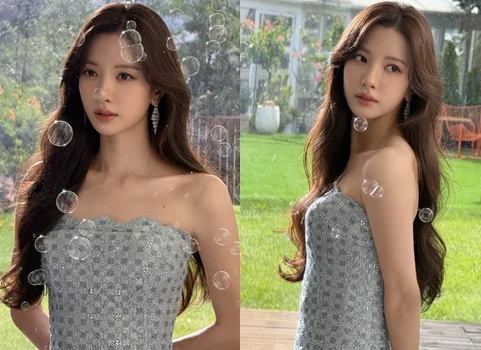 WJSN Bona posing in an off-the-shoulder dress in front of green grass