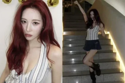 Sunmi posing on stairs in a striped halter top and denim miniskirt holding a digital camera