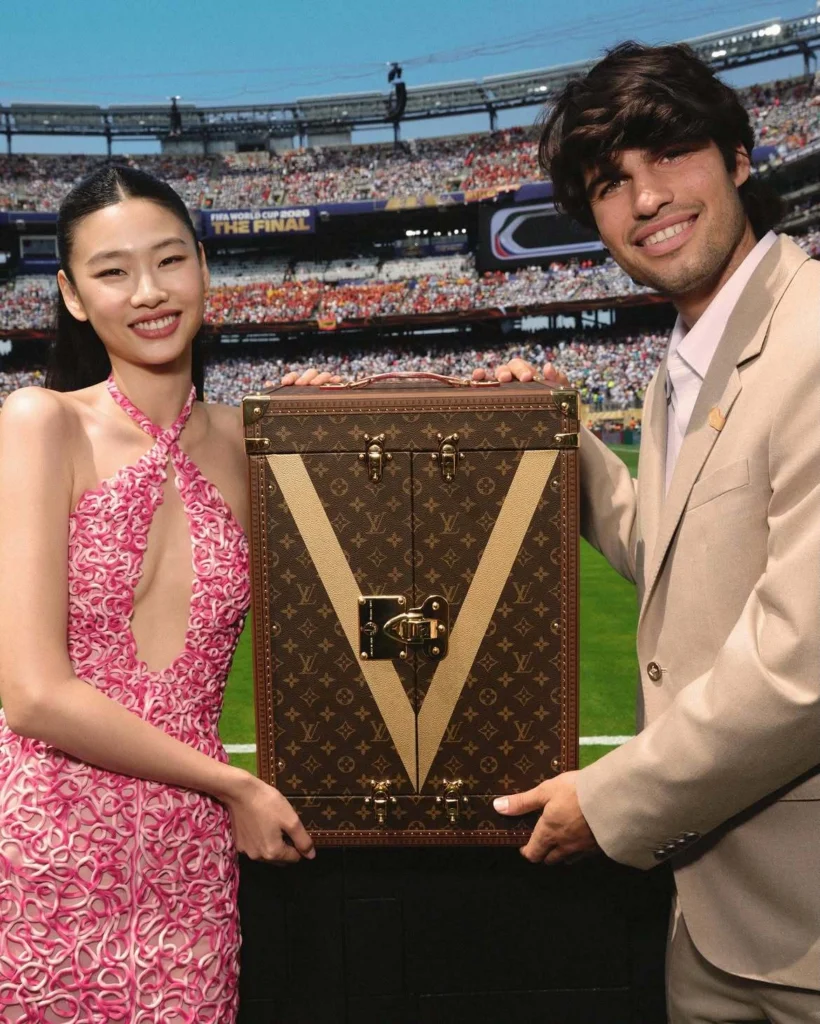Jung Ho Yeon and Carlos Alcaraz presenting the FIFA World Cup trophy in a Louis Vuitton trunk